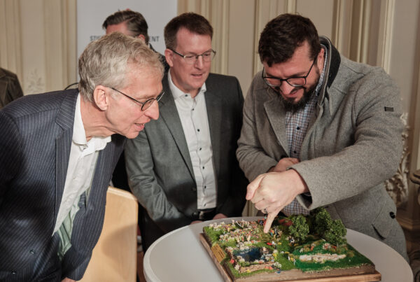230108_RHSM_Neujahrsempfang 1 Teilnehmende betrachten gemeinsam ein Landschaftsmodell auf einem Tisch.
