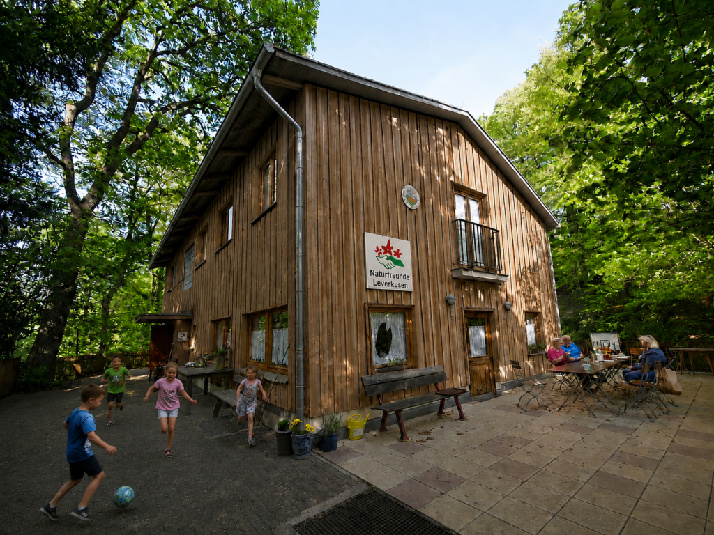 Zukunftsvision eines holzverkleideten NaturFreundeHauses mit Außenbereich für Spiel und Begegnung.